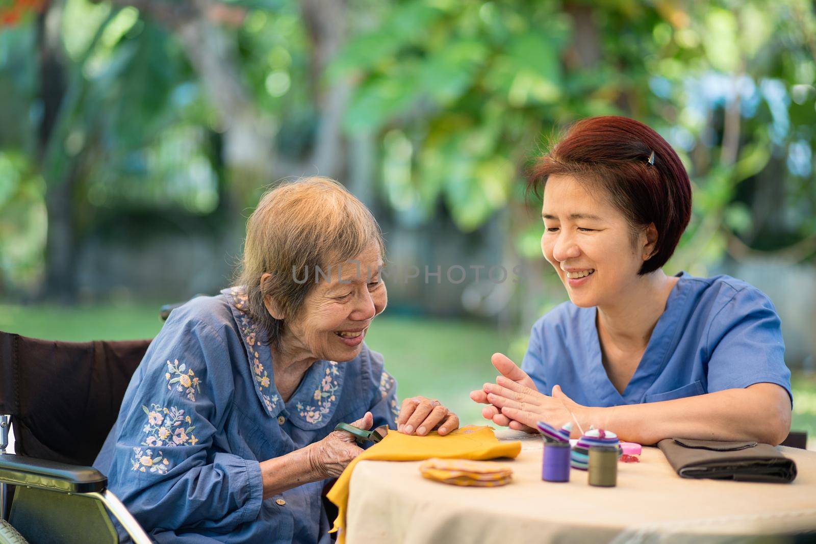 Elderly woman with caregiver in the needle crafts occupational therapy  for Alzheimer’s or dementia by toa55