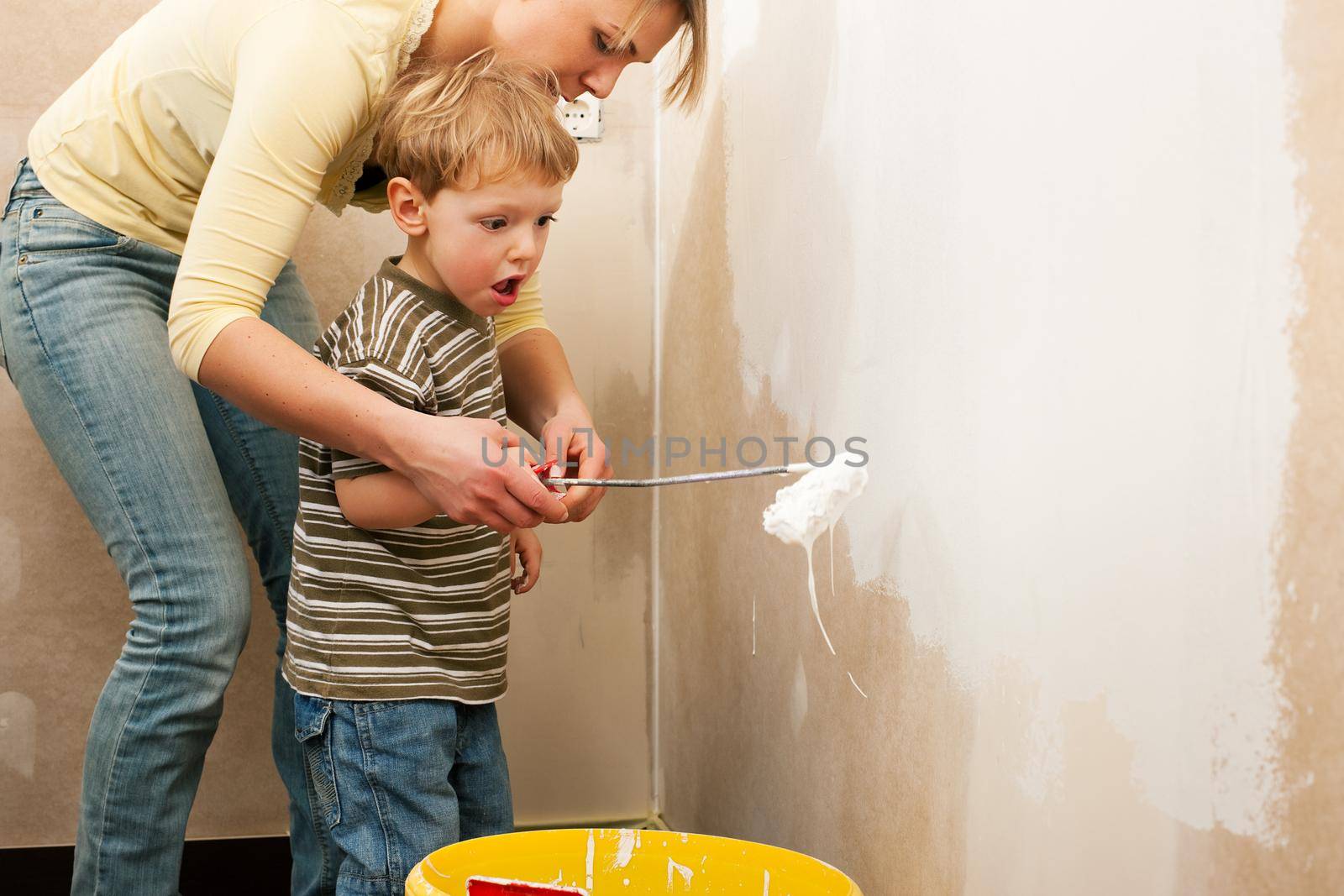 Family - mother with son - painting the wall of their new home or apartment, apparently they just moved in