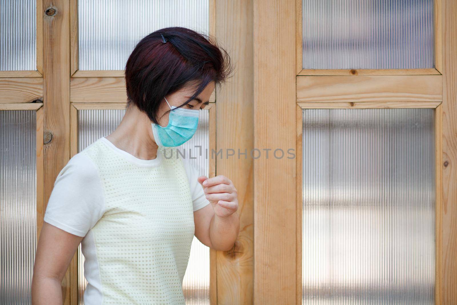 Woman wearing mask opening the door with the elbow for protection  infection COVID-19