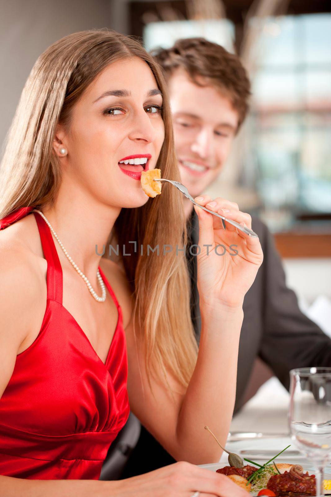 Portrait of attractive female eating food with her boyfriend in restaurant