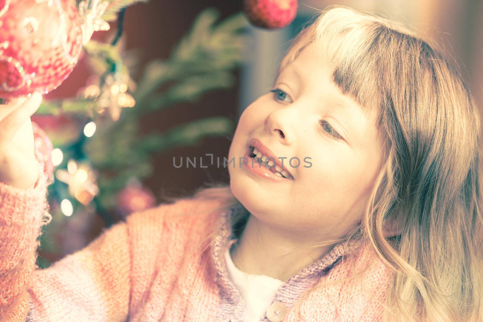 Young girl decorating the Christmas tree, holding some Christmas by Kzenon