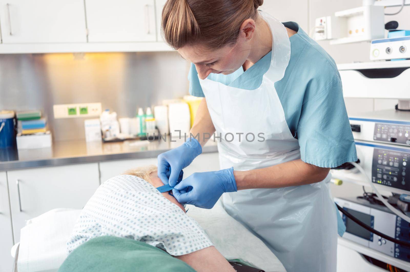 Nurse preparing patient for gastroscopy putting harness for tube on