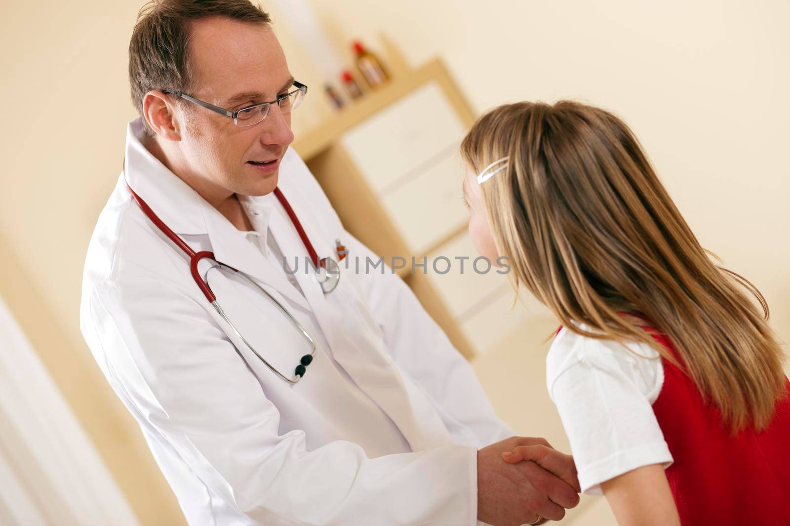 Doctor greeting child patient with handshake by Kzenon