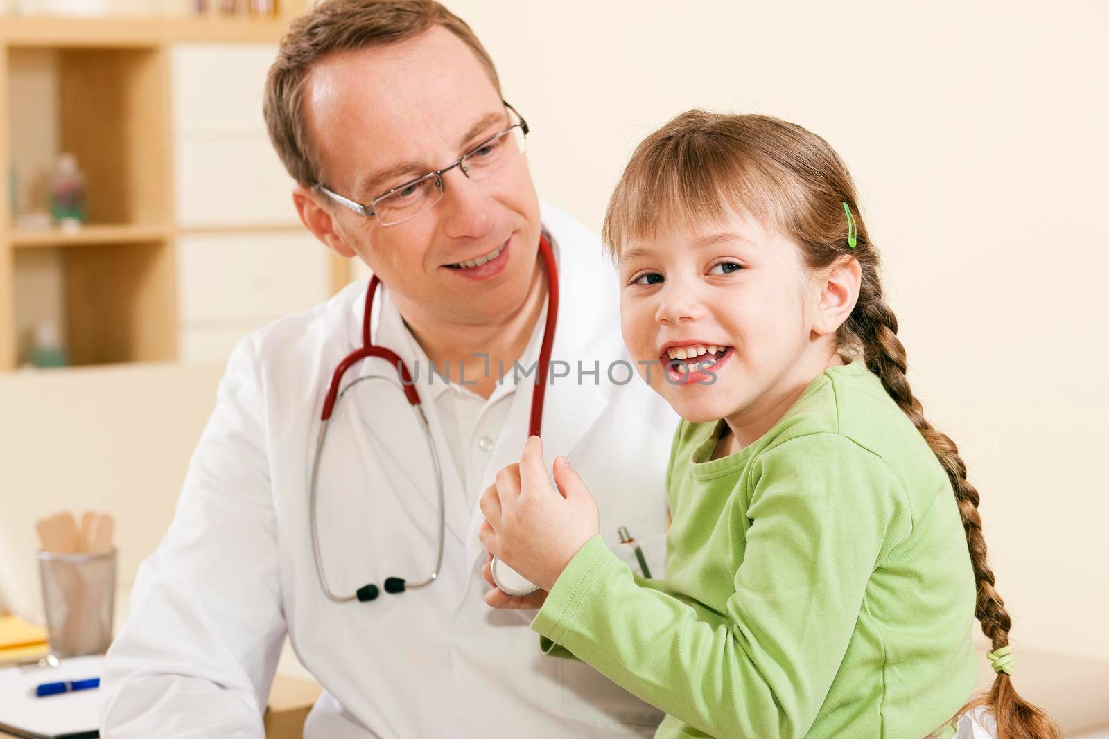 Pediatrician doctor with child patient  by Kzenon