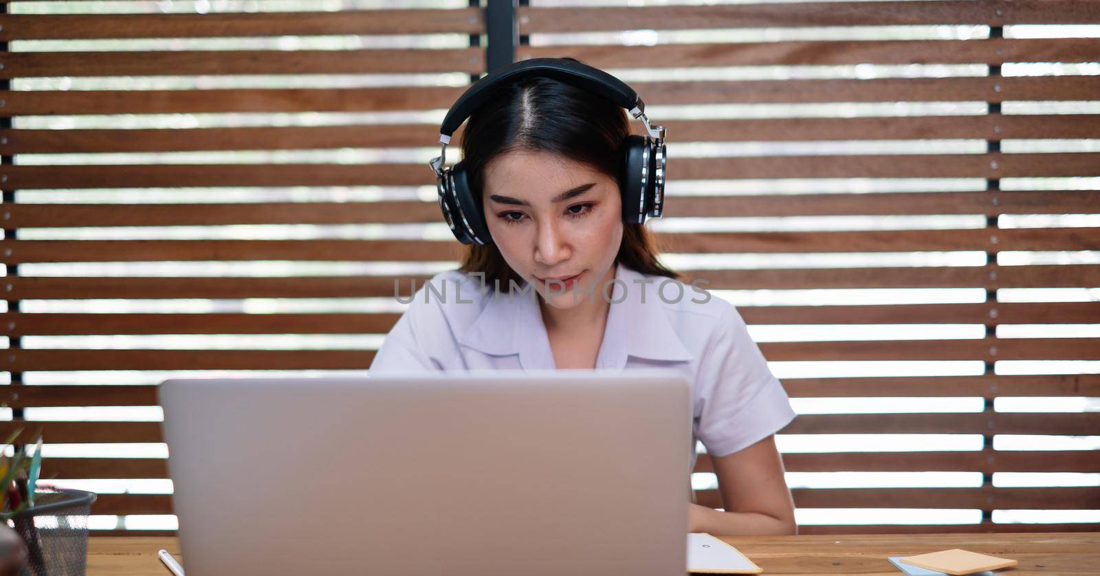 Young beautiful female using laptop computer for studying or entrepreneur working with a laptop and notes at home by nateemee