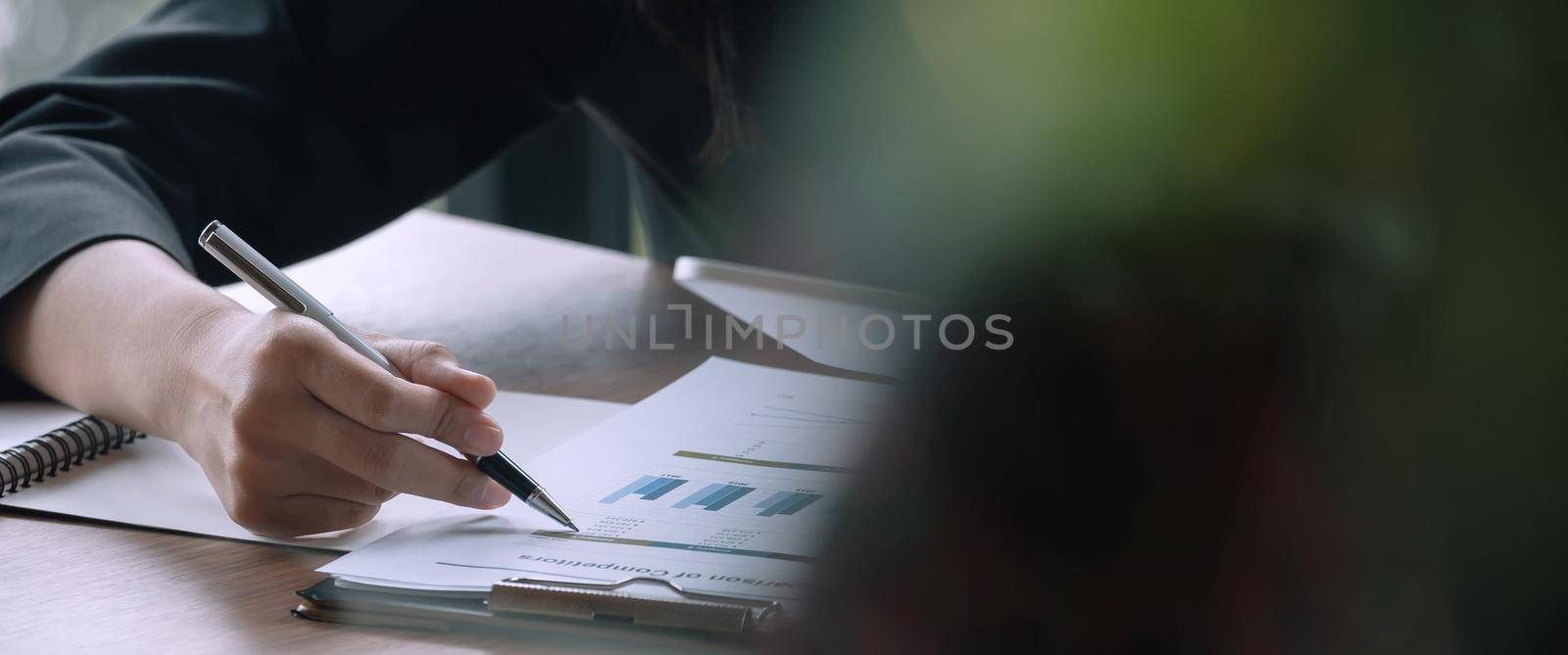 Close up businessman pen pointing turnover with graph chart report and use laptop computer for analysis data.