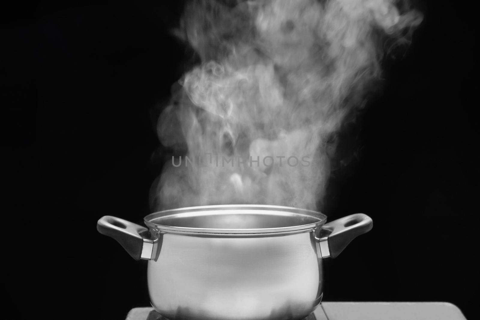 steam over cooking pot in kitchen on dark background by toa55