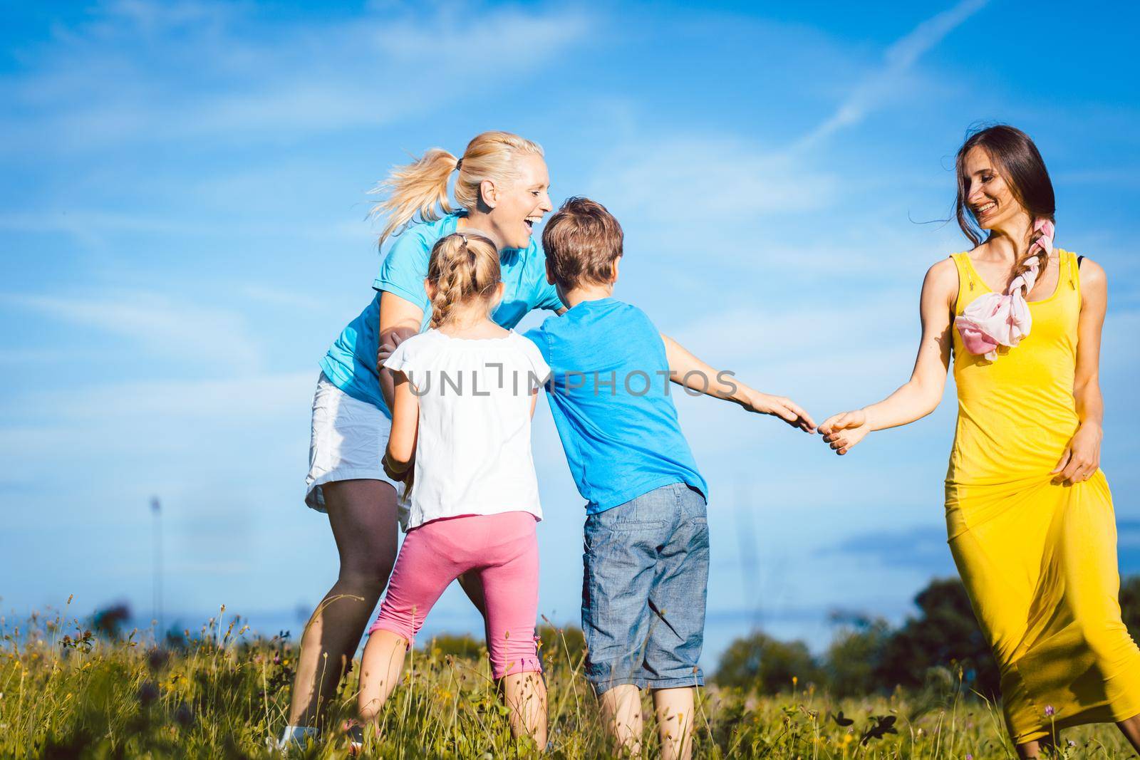 Two women with children playing tag by Kzenon