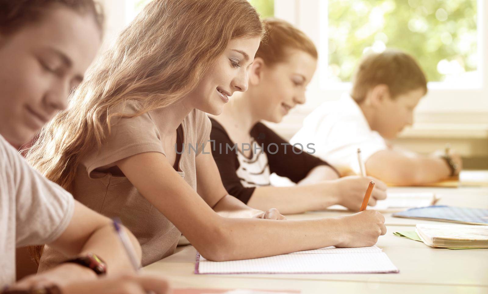 Students writing a test in school class by Kzenon