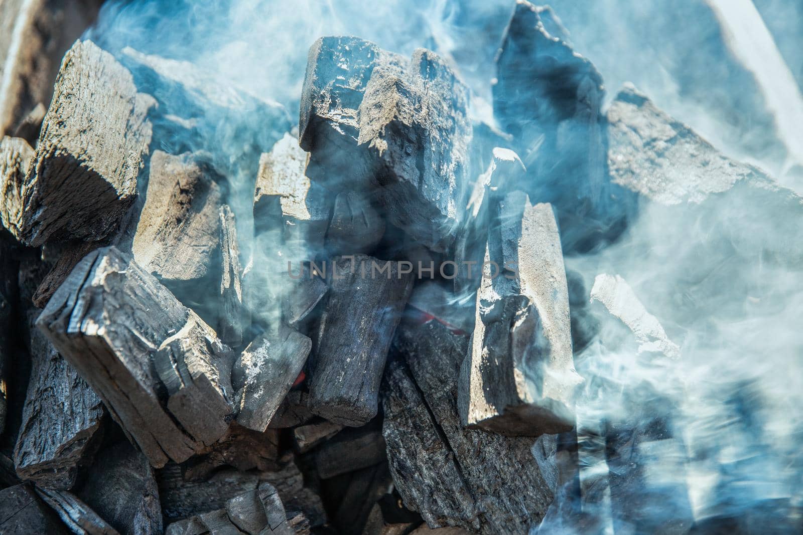 Close up of charcoal is starting to burn in the kitchen grill.  Hot charcoal and flame with smoke. by toa55