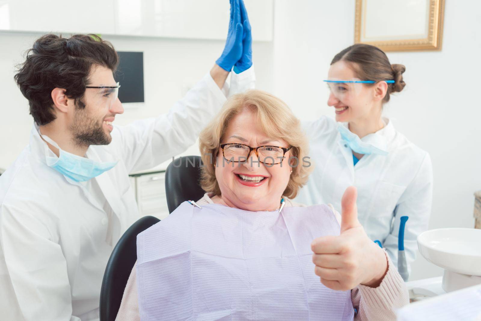 Dentists and patient in surgery being excited by Kzenon