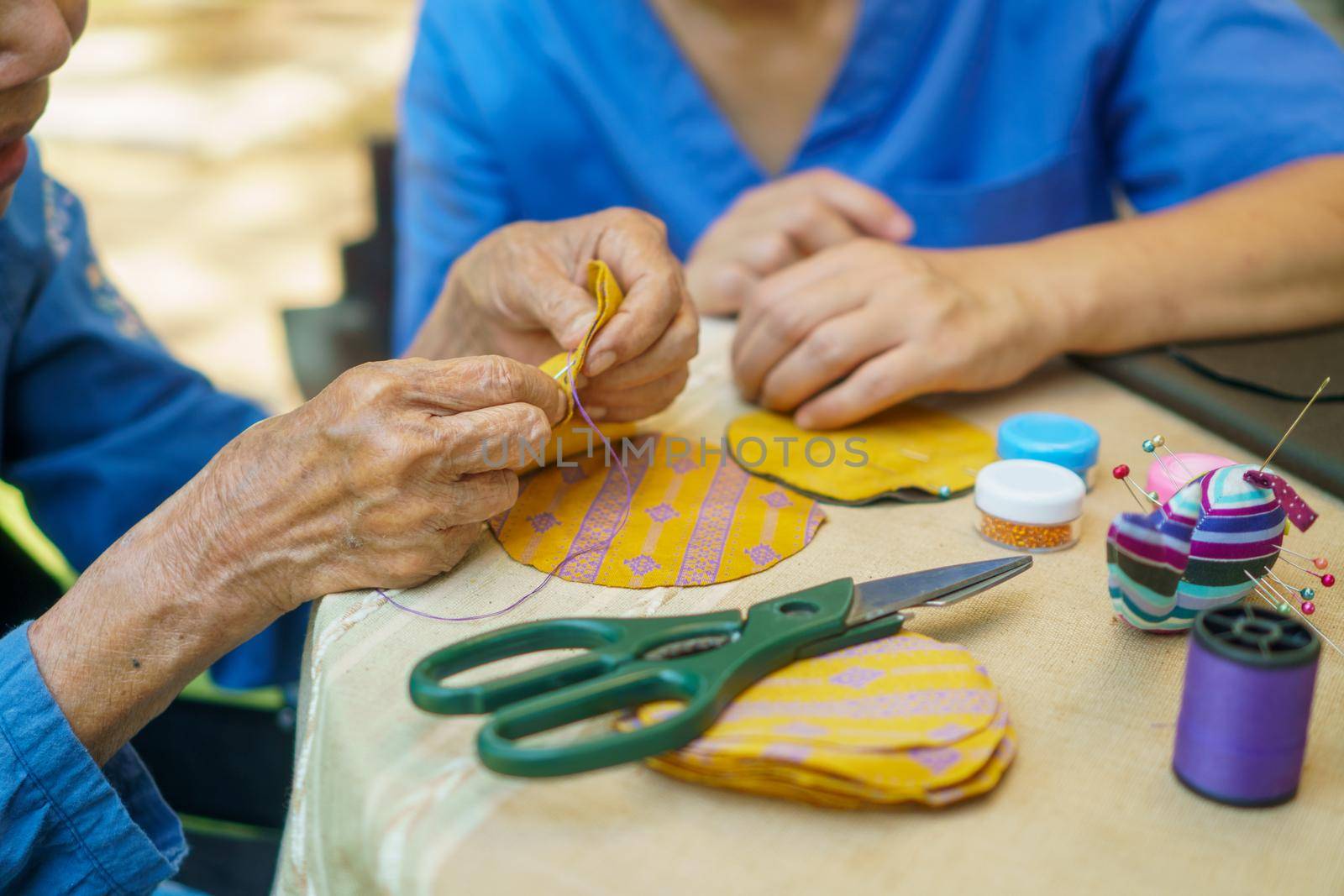 Elderly woman with caregiver in the needle crafts occupational therapy  for Alzheimer’s or dementia by toa55