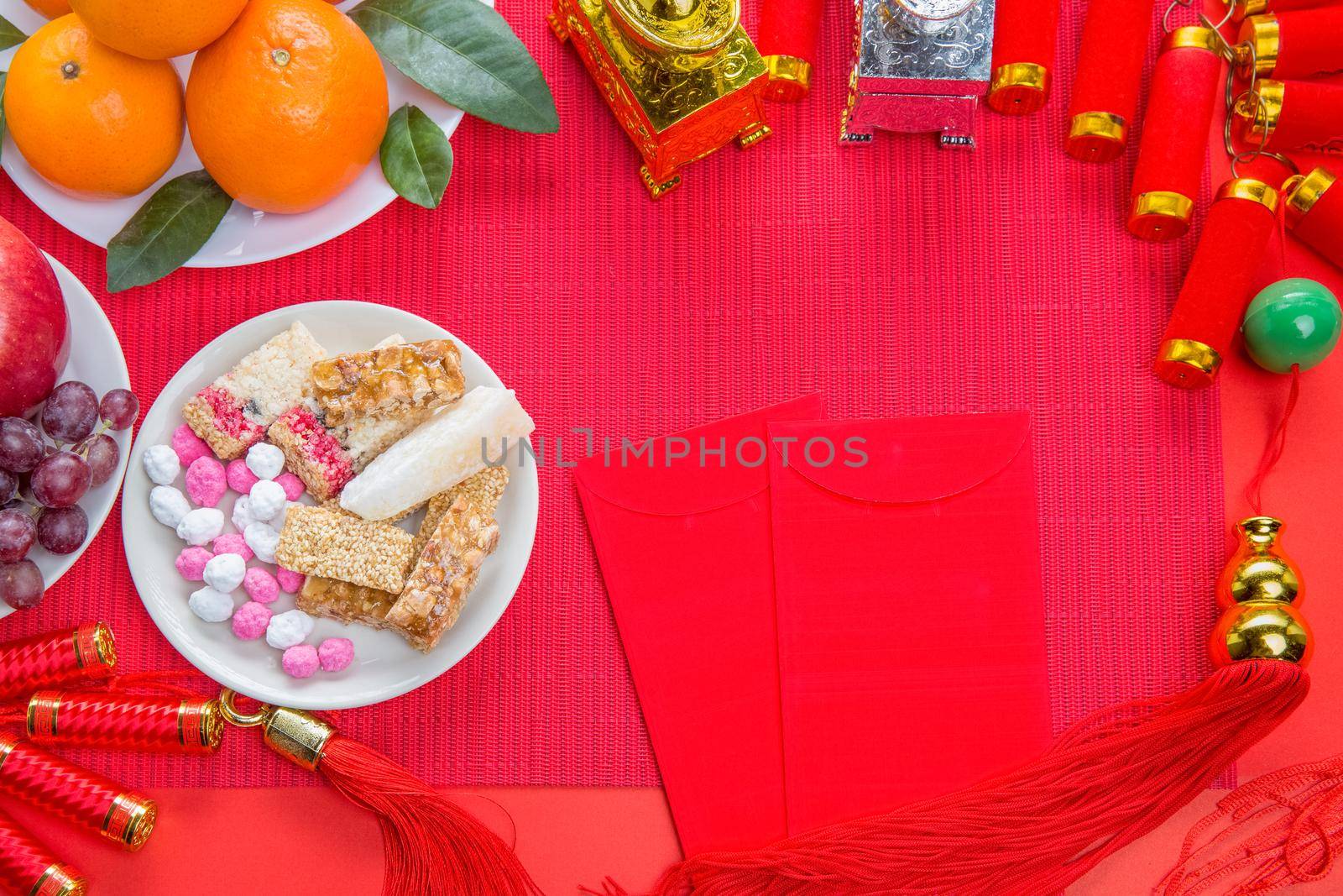 Flat lay Chinese new year festival decorations with orange apple grape and red packet. Texts appear in image meaning good fortune