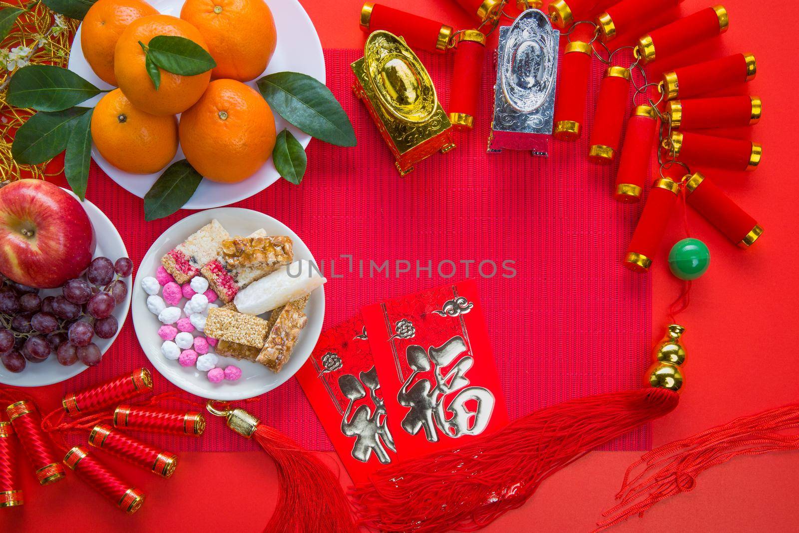 Flat lay Chinese new year festival decorations with orange apple grape and red packet. Texts appear in image meaning good fortune by toa55