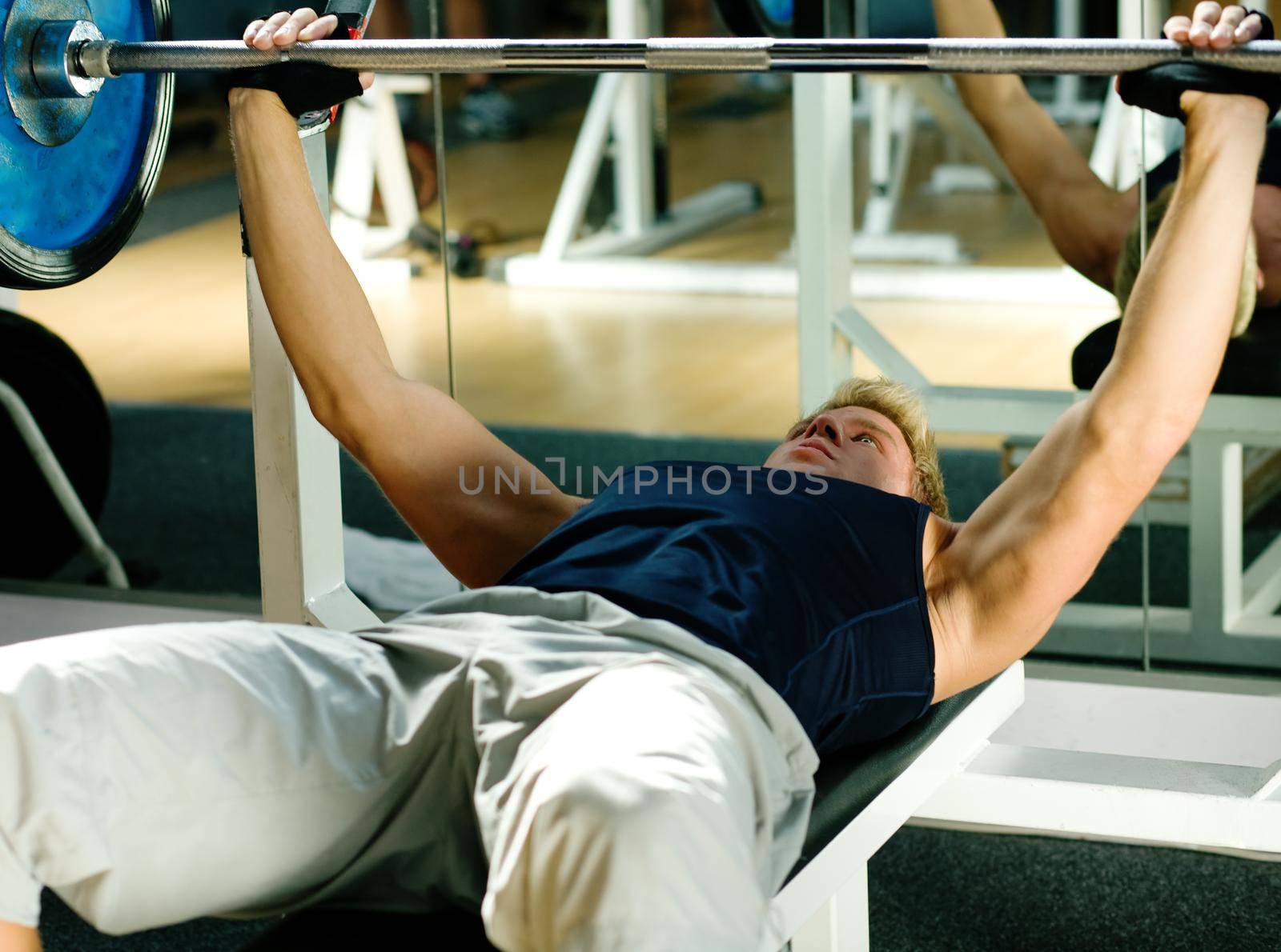 Man lifting a barbell in a gym doing body building exercises
