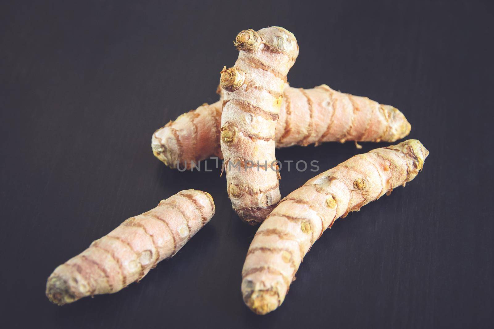 Turmeric root on a black wooden table. Close-up view