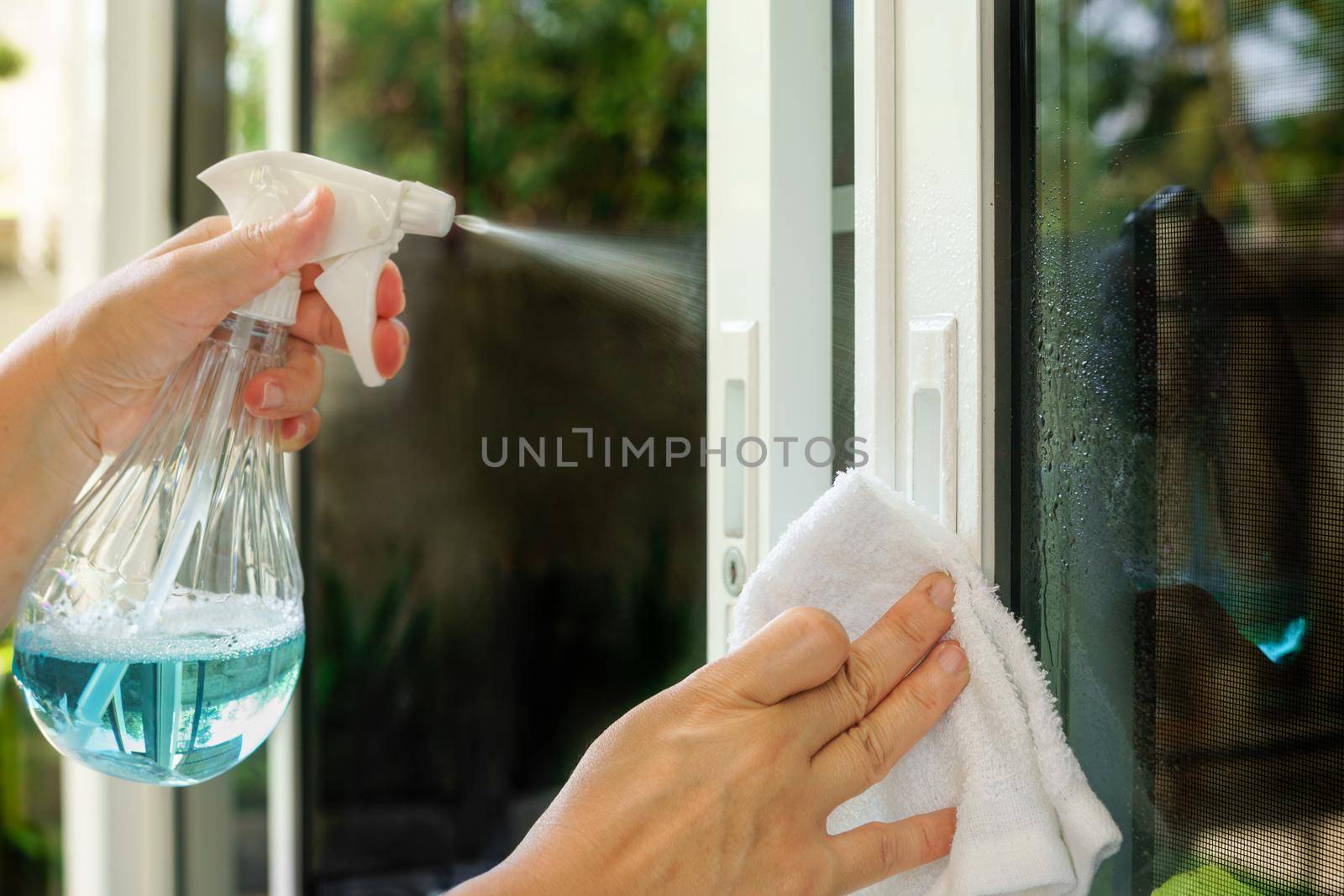 Woman is cleaning door handle with alcohol spray for  Covid-19 (Coronavirus) prevention.