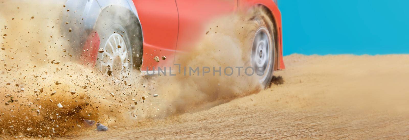 Gravel splashing from rally race car drift on track.