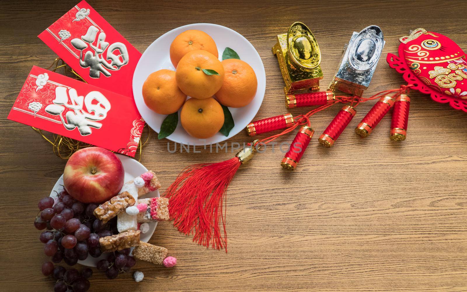 Flat lay Chinese new year festival decorations with orange apple grape and red packet. Texts appear in image meaning good fortune by toa55