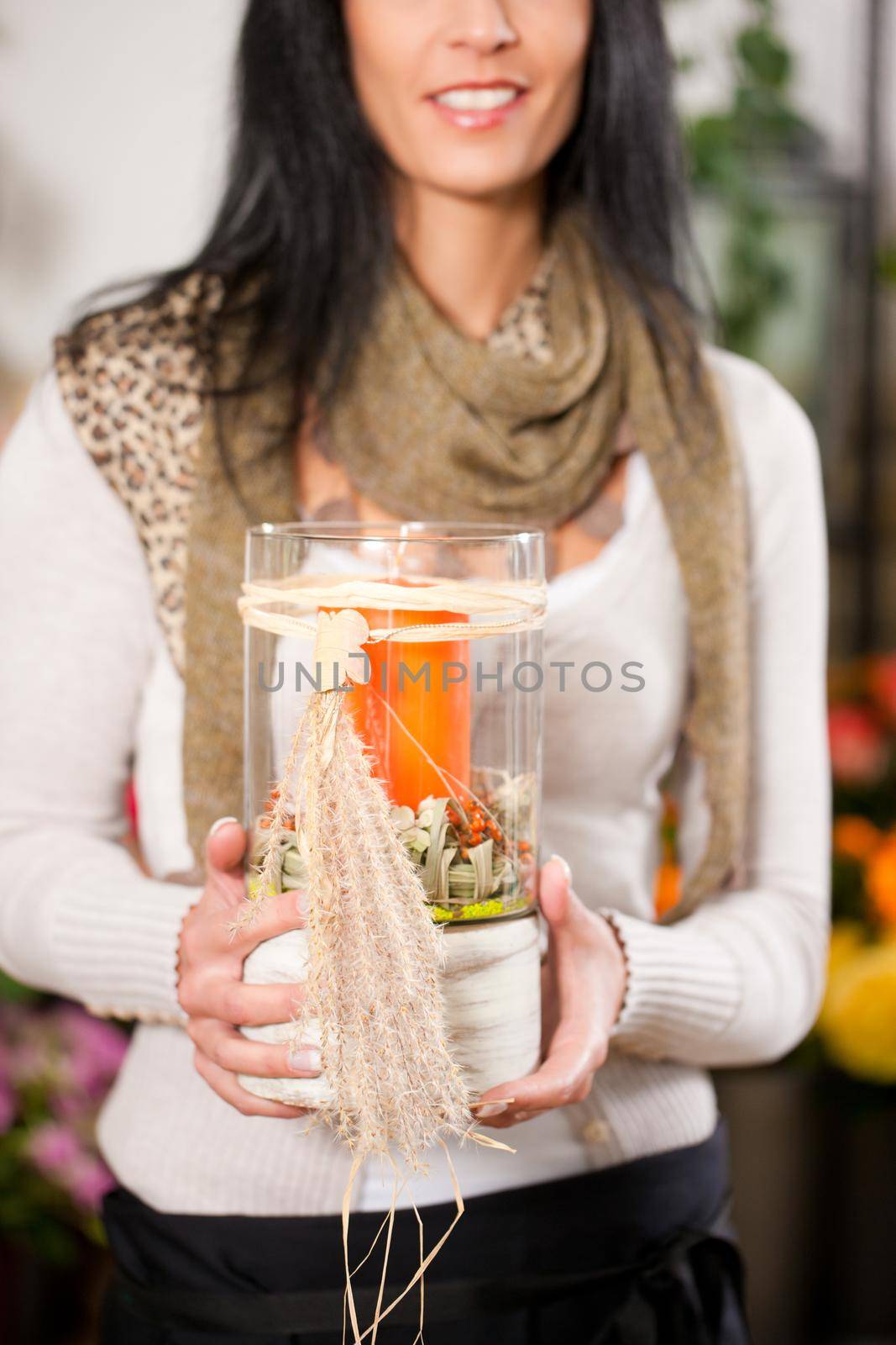 Female florist in flower shop or nursery with candle in glass