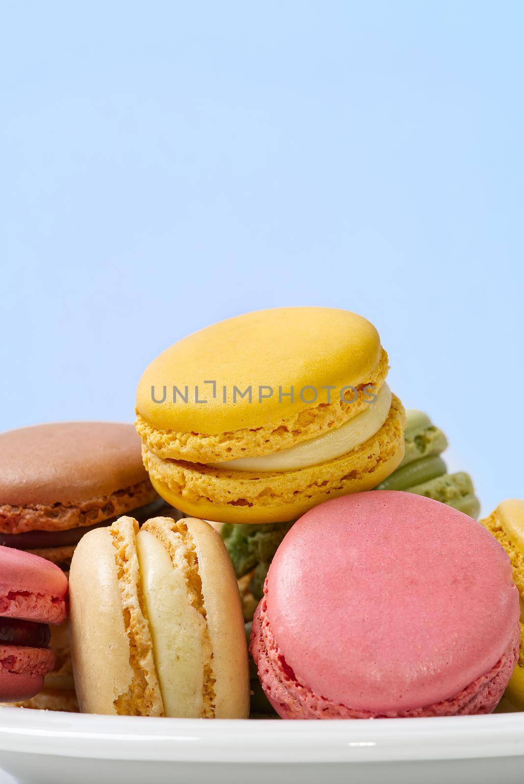 French dessert macaron isolated on blue background. Modern Macarons on colorful background. by PhotoTime