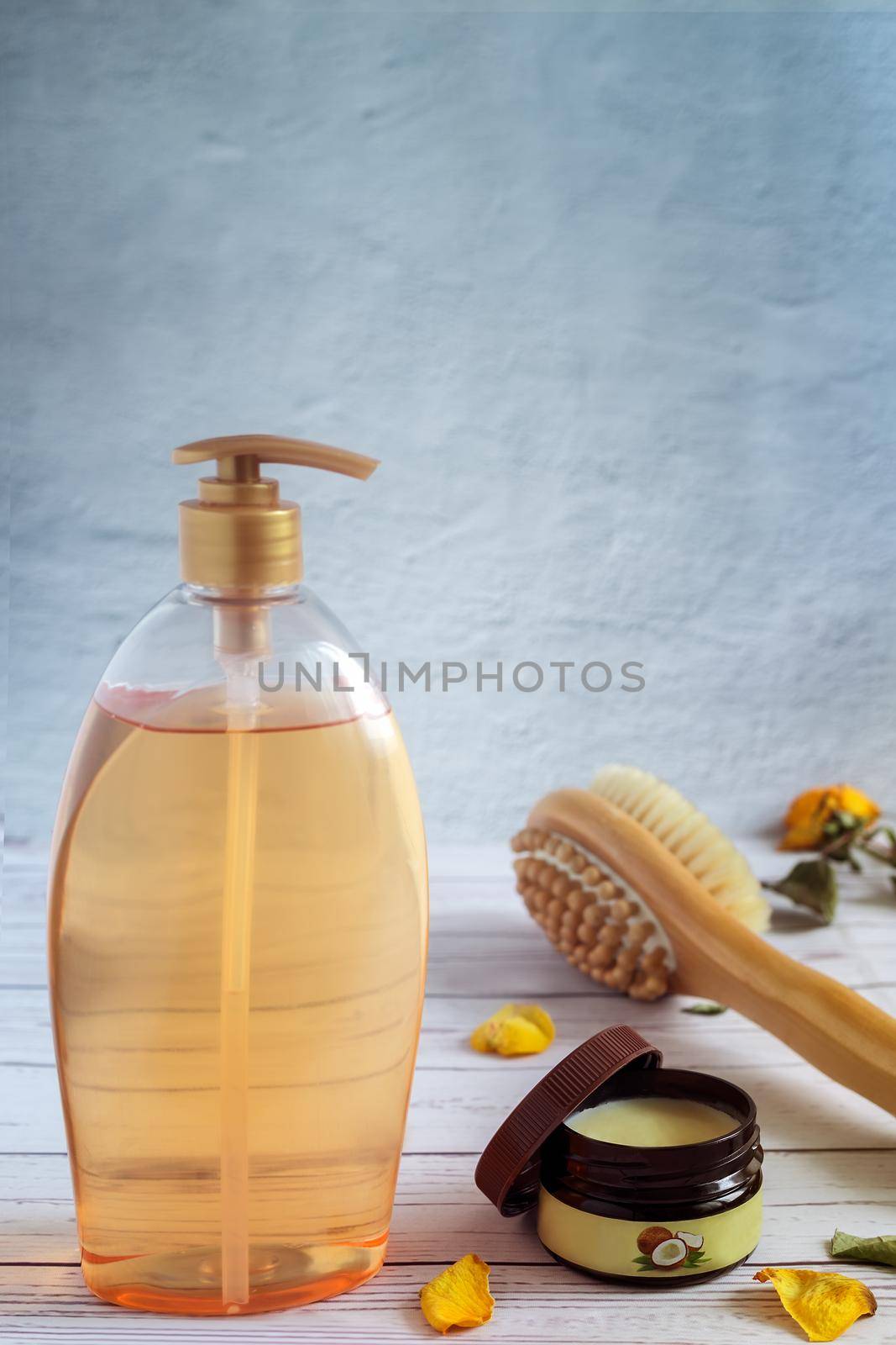 Shower gel in a large bottle, body massage brush and coconut oil for skin care.