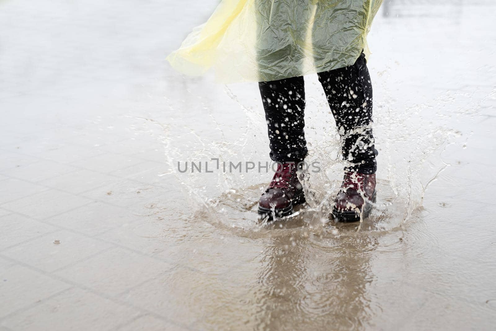 woman running on asphalt in rainy weather. Close up of legs and shoes splashing in puddles.