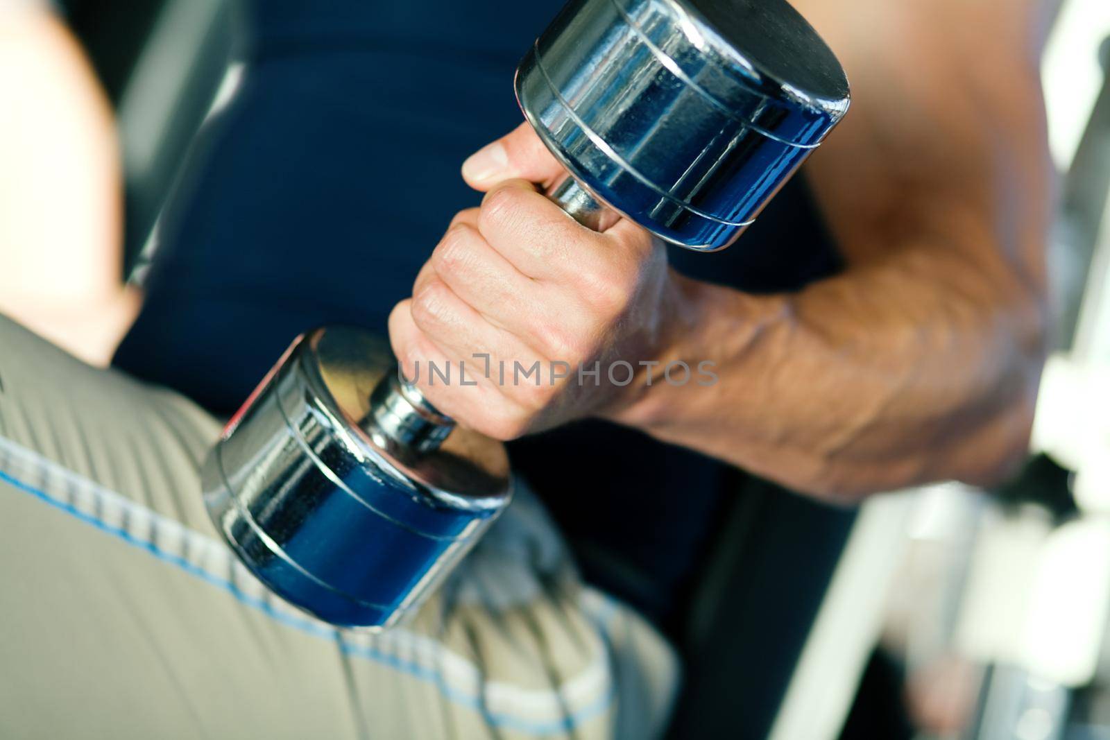 Strong man with dumbbells; focus on hand and dumbbell