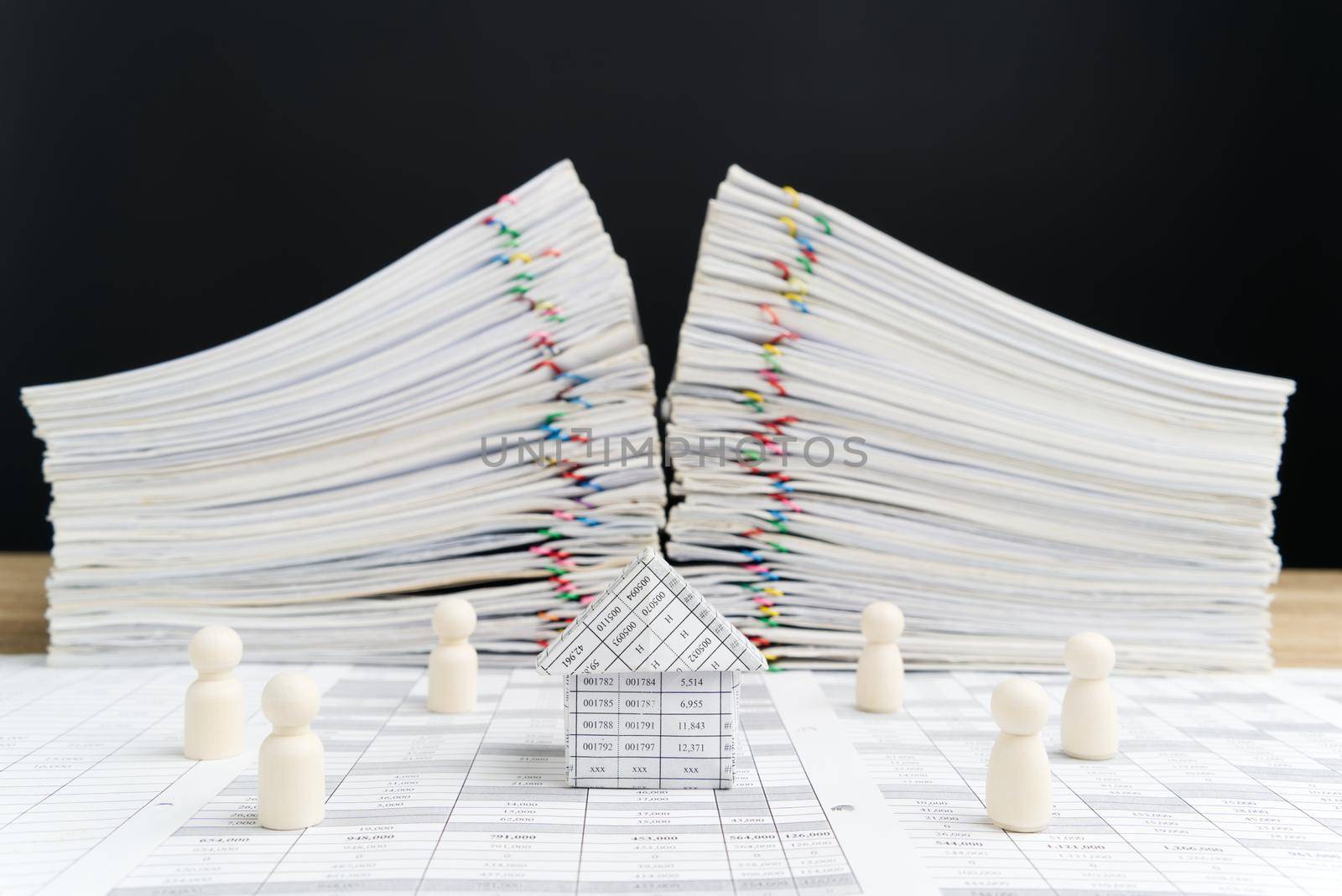 House surrounded by wooden dolls have blur overload paperwork financial report of sale with black background and copy space. Business and finance concept network system connection and communication.