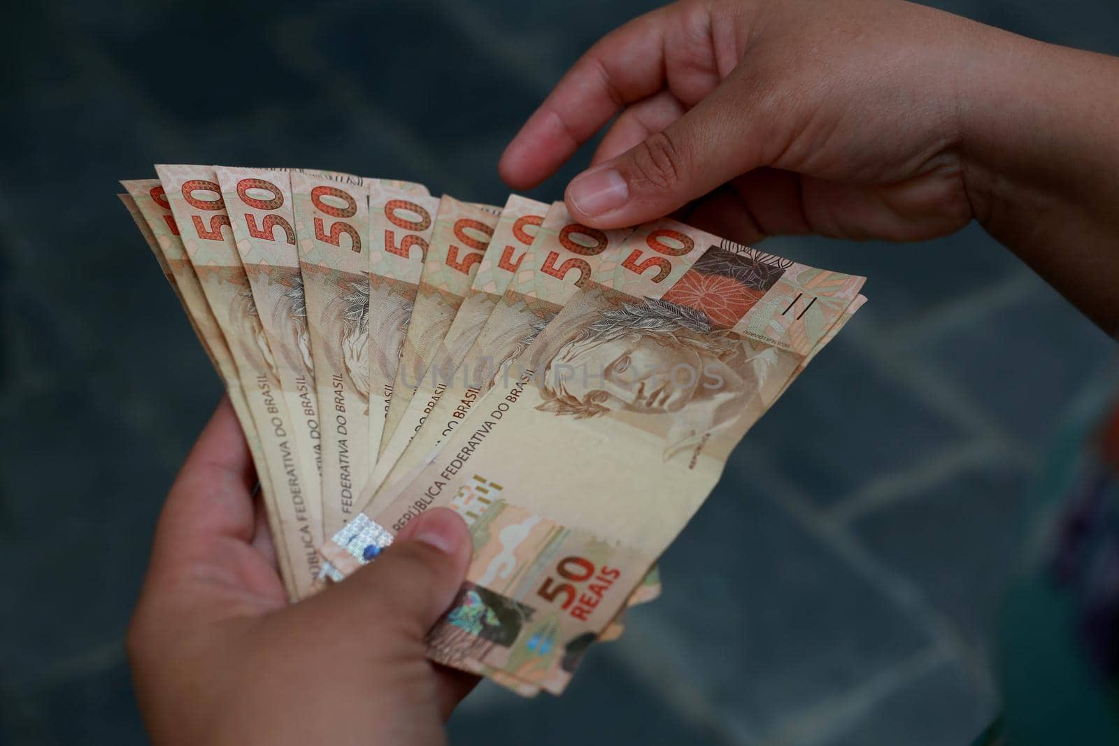 salvador, bahia / brazil - february 25, 2015: hands hold fifty reais (R $ 50.00) bills in the city of Salvador.




