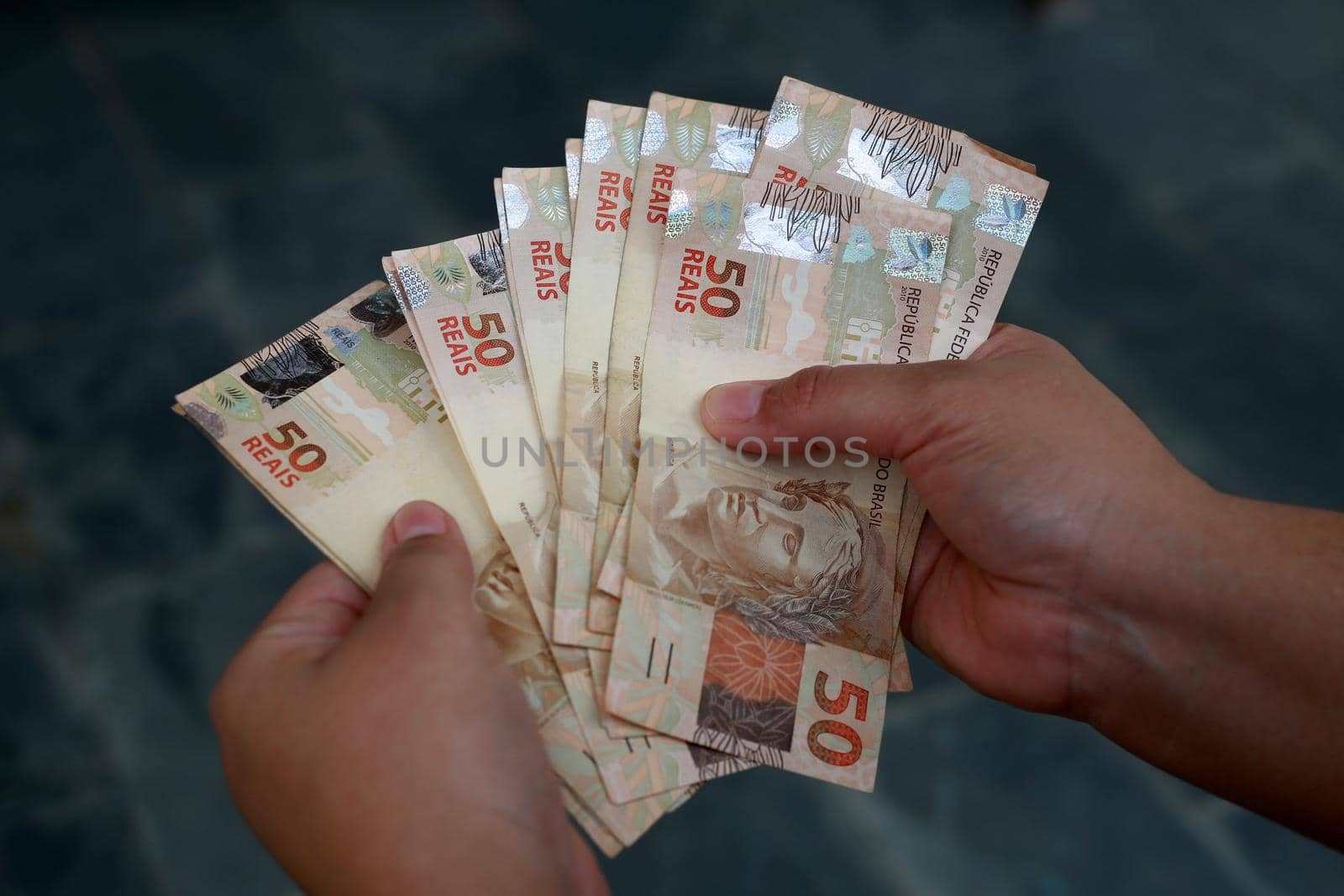 salvador, bahia / brazil - february 25, 2015: Hands hold fifty reais banknotes during counting. R$ 50.

