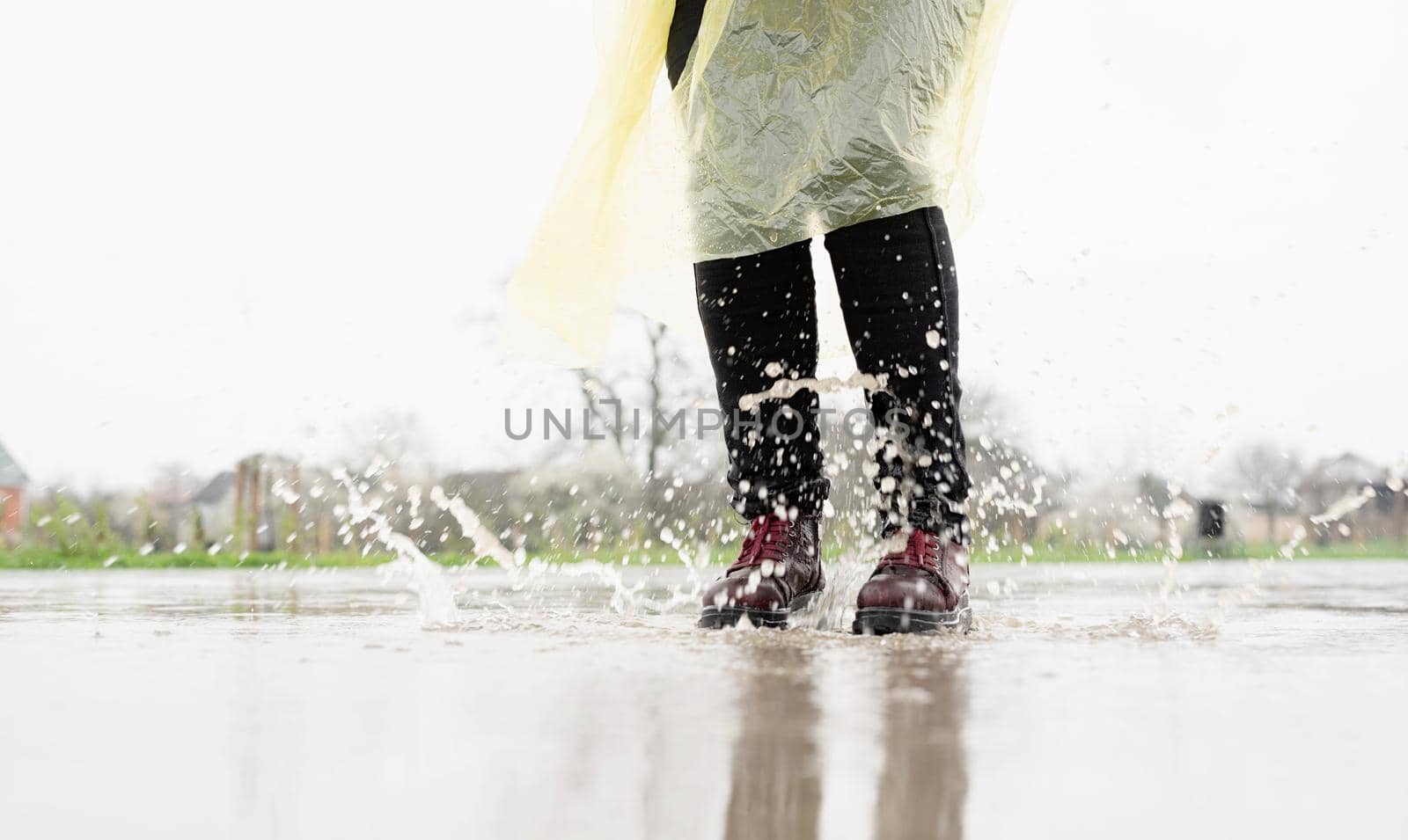 woman running on asphalt in rainy weather. Close up of legs and shoes splashing in puddles.