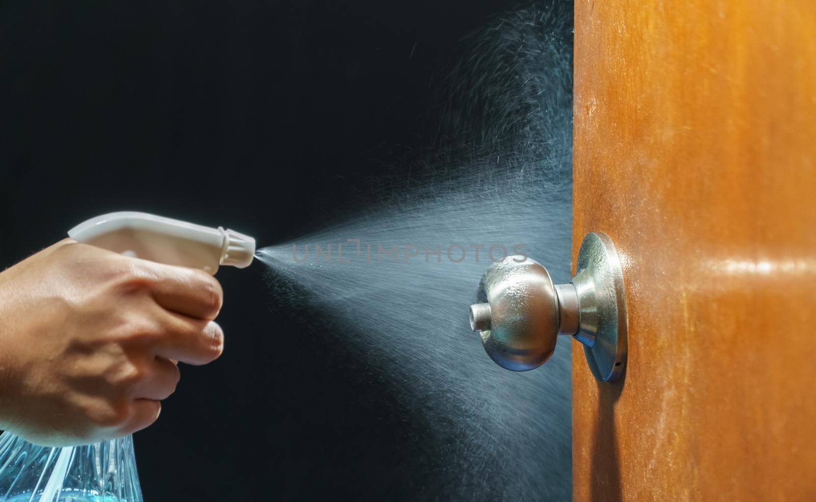 Cleaning door knob with alcohol spray for  Covid-19 (Coronavirus) prevention.