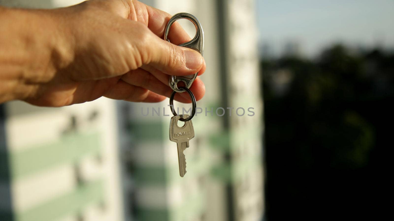 salvador, bahia brazil - may 26, 2020: hand holds apartment key next to a residential building