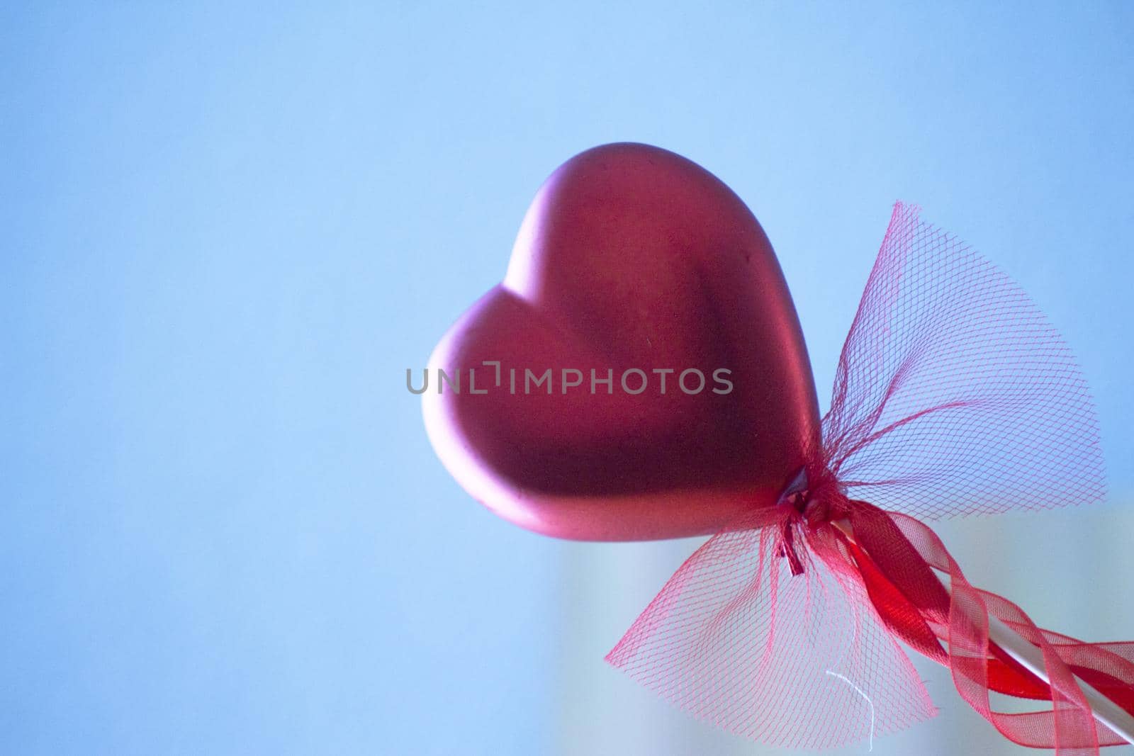 Red heart attached to a stick with a bow hanging. No people