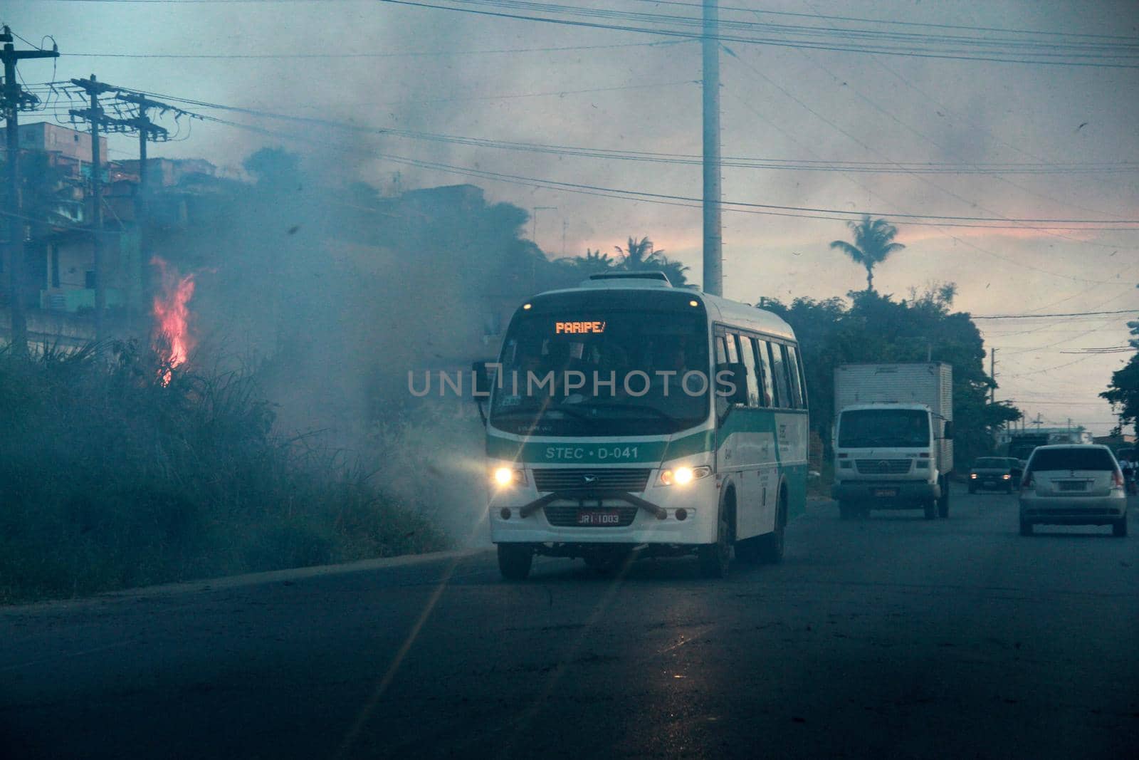 salvador, bahia / brazil - november 29, 2012: vehicles are seen roaming near the smoke from burning vegetation on the BA 528 highway, Fazenda Coutos region in the city of Salvador.