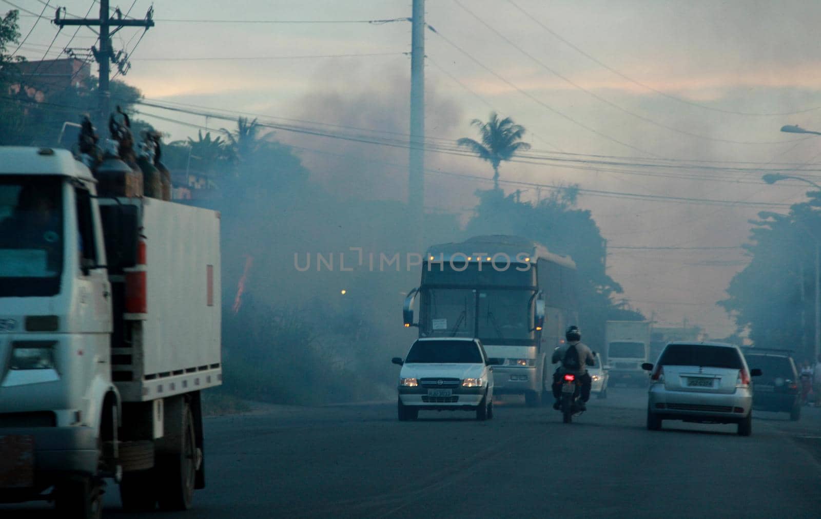salvador, bahia / brazil - november 29, 2012: vehicles are seen roaming near the smoke from burning vegetation on the BA 528 highway, Fazenda Coutos region in the city of Salvador.