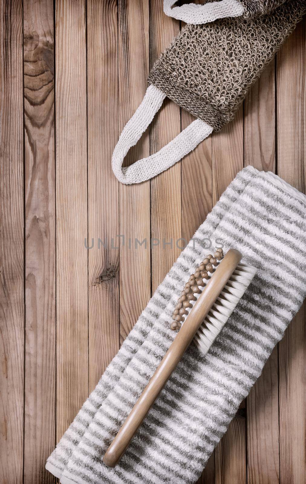Accessories for visiting the bath or sauna on a wooden background: towel, washcloth, massage brush. Top view with copy space. Flat lay