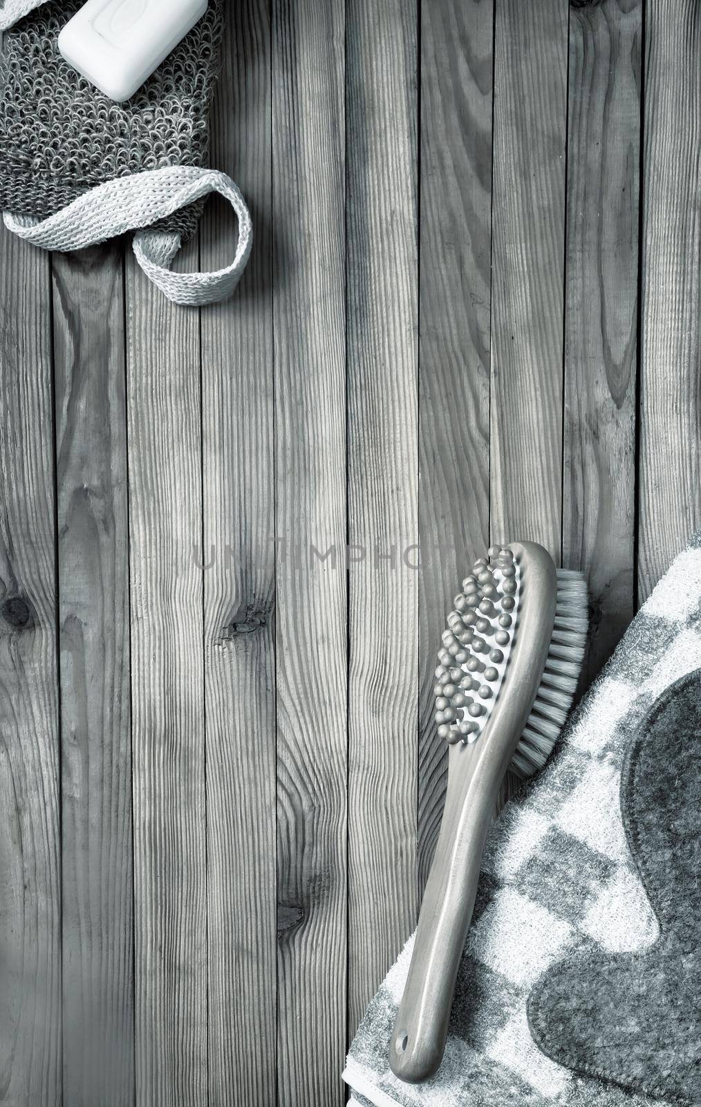 Accessories for visiting a bath or sauna on a wooden background: towel, washcloth, massage brush, soap, glove. Top view with copy space. Flat lay