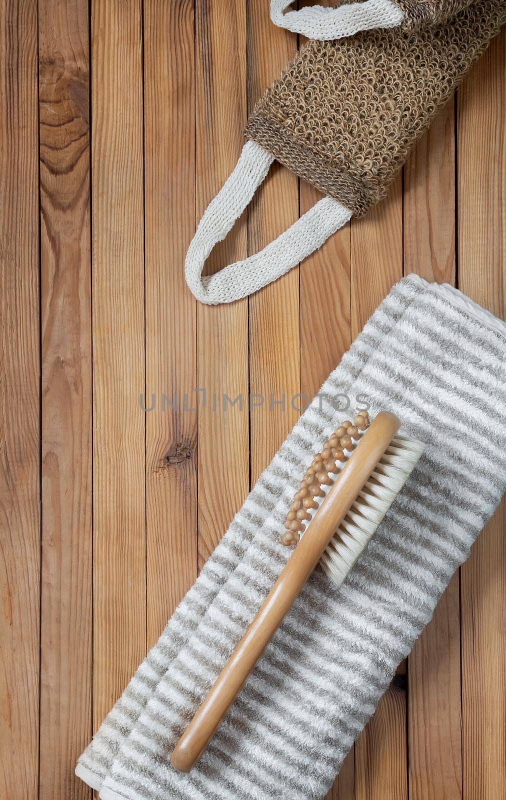 Accessories for visiting the bath or sauna on a wooden background: towel, washcloth, massage brush. Top view with copy space. Flat lay