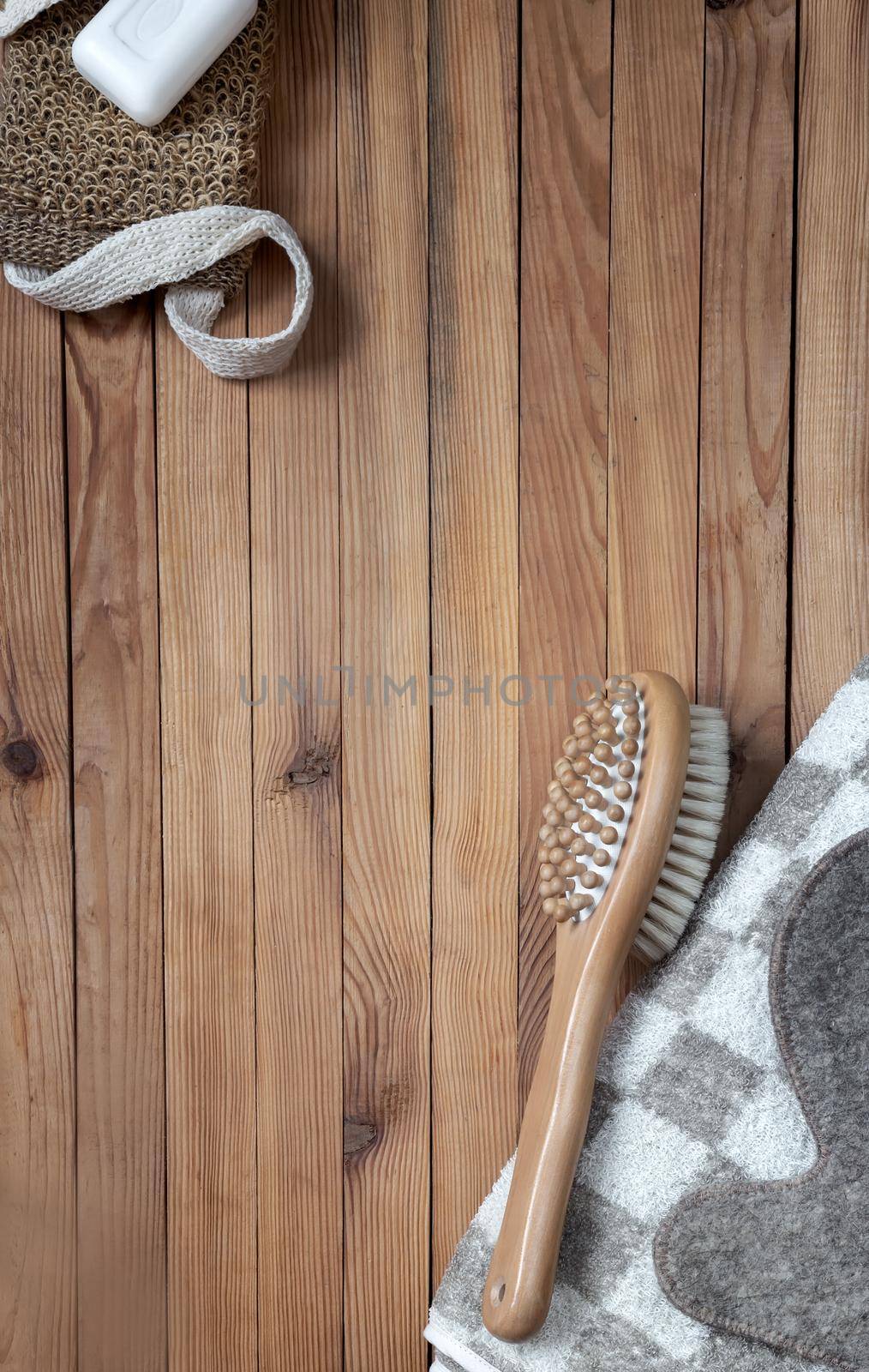 Accessories for visiting a bath or sauna on a wooden background: towel, washcloth, massage brush, soap, glove. Top view with copy space. Flat lay