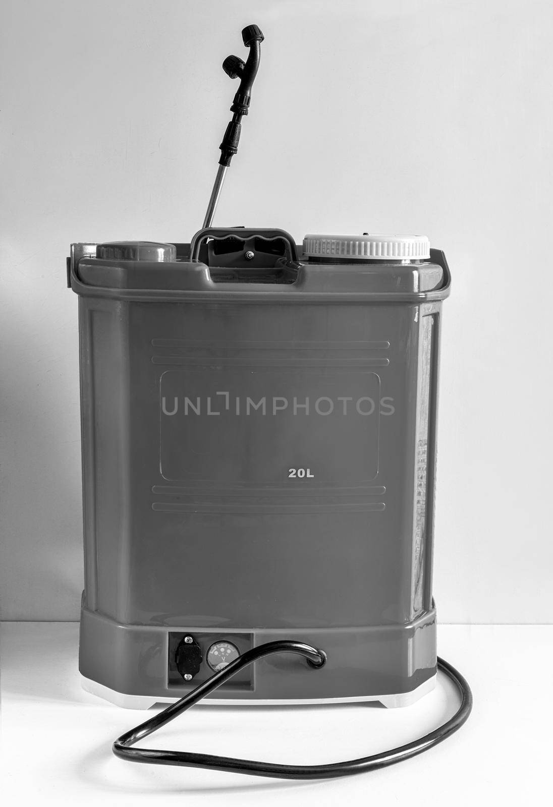 Backpack battery sprayer for protecting trees and plants from diseases and pests. The pressure is increased using a battery-powered pump. Black and white image, copy space