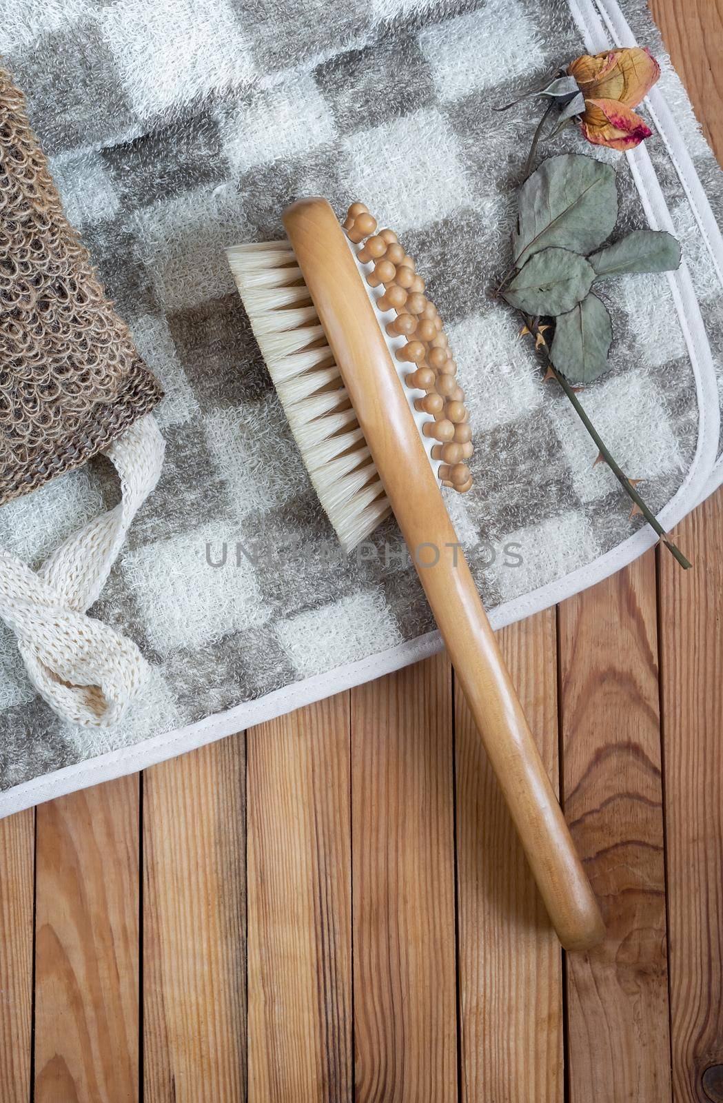 Accessories for visiting a bath or sauna on a wooden background: a washcloth, a massage towel and a massage brush. Top view with copy space. Flat lay