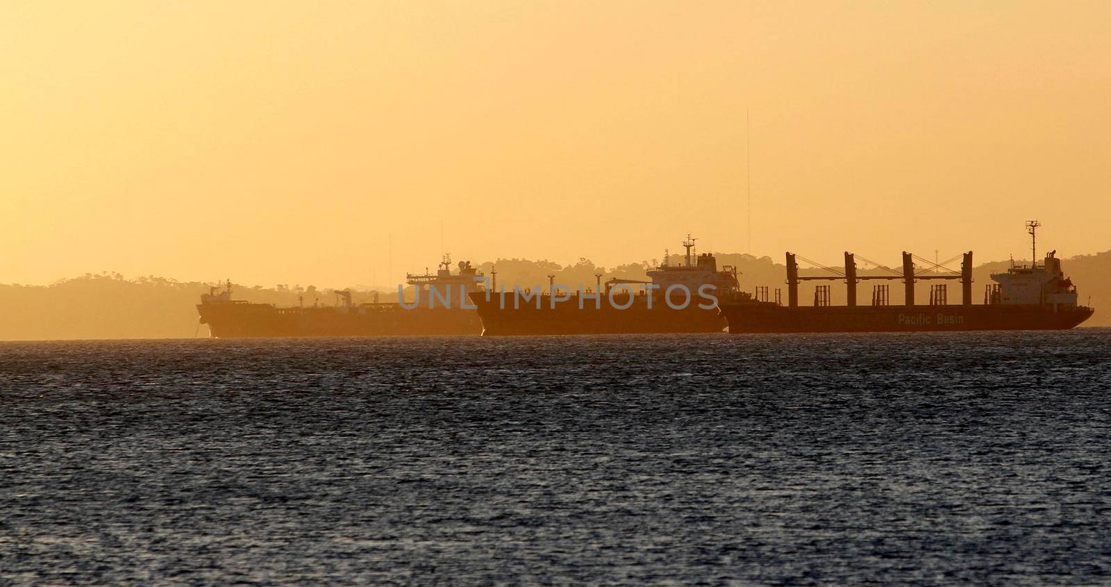 salvador, bahia / brazil - october 1, 2014: cargo ship is seen alongside a sailboat in the waters of Baia de Todos os Santos, in the city of Salvador.