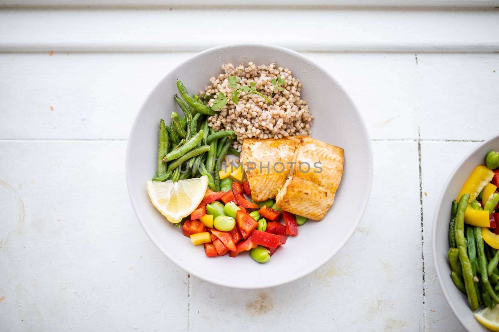Top view of salmon and buckwheat dish with green beans, broad beans, and tomato slices. Nutritious dishes with vegetables and fish from above. Healthy balanced diet