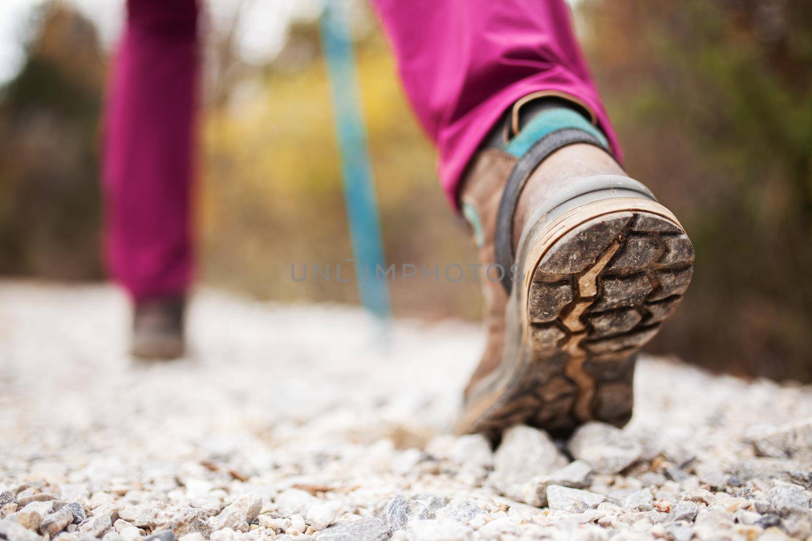 Hiking girl in nature. Low angle view of generic sports shoe and legs on pebble dirt road. Healthy fitness lifestyle outdoors. by kokimk