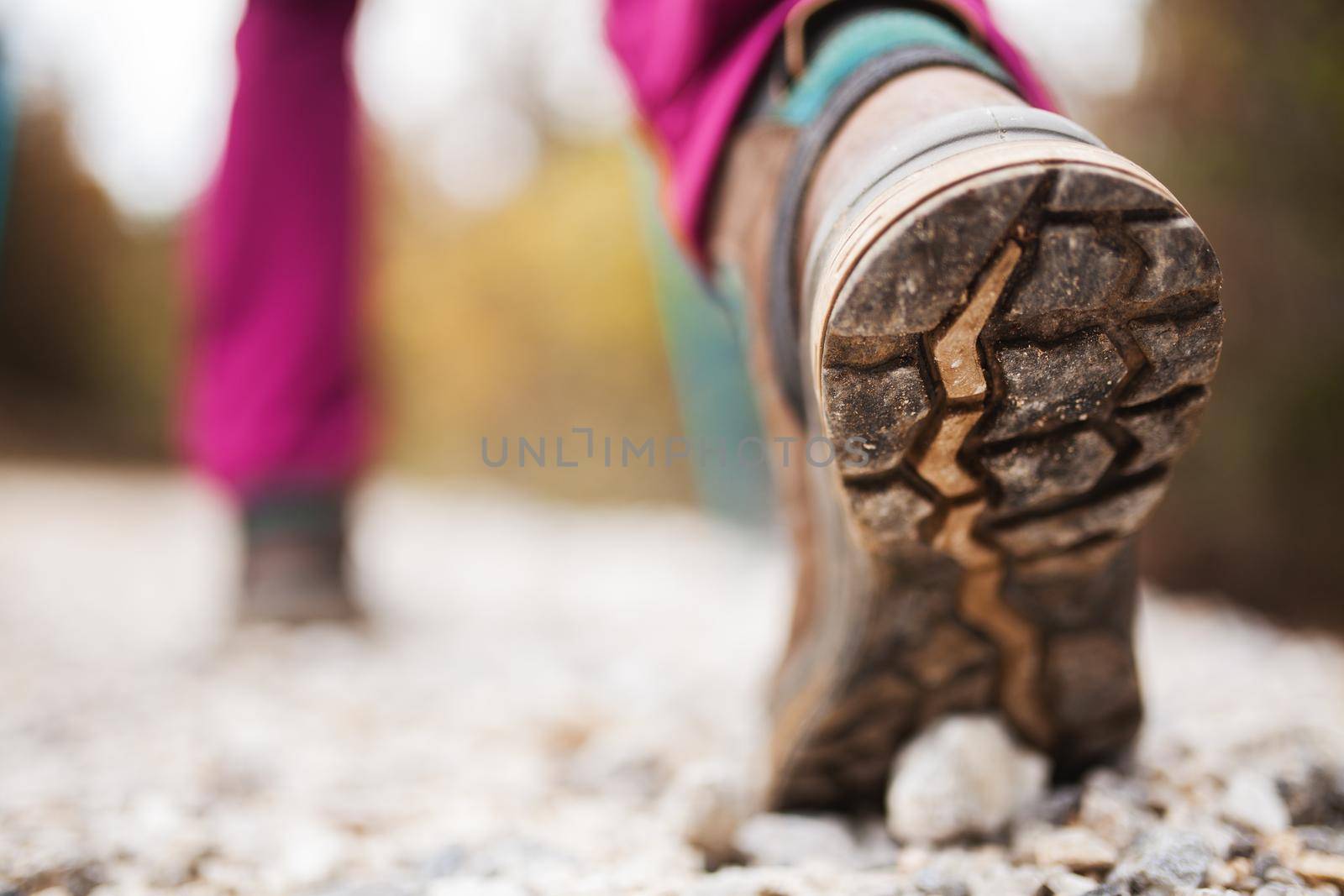 Hiking girl in nature. Low angle view of generic sports shoe and legs on pebble dirt road. Healthy fitness lifestyle outdoors.