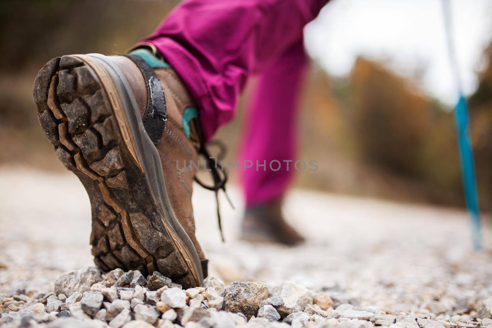 Hiking girl in nature. Low angle view of generic sports shoe and legs on pebble dirt road. Healthy fitness lifestyle outdoors. by kokimk