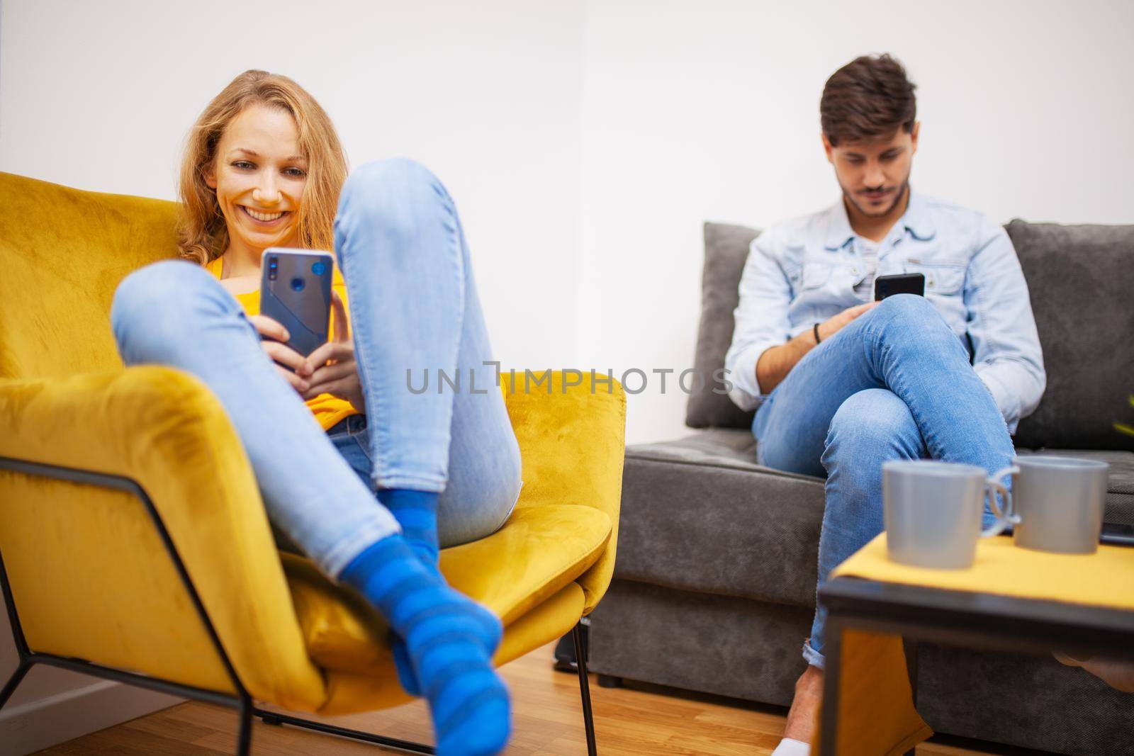 couple at home looking at their smart phones by kokimk