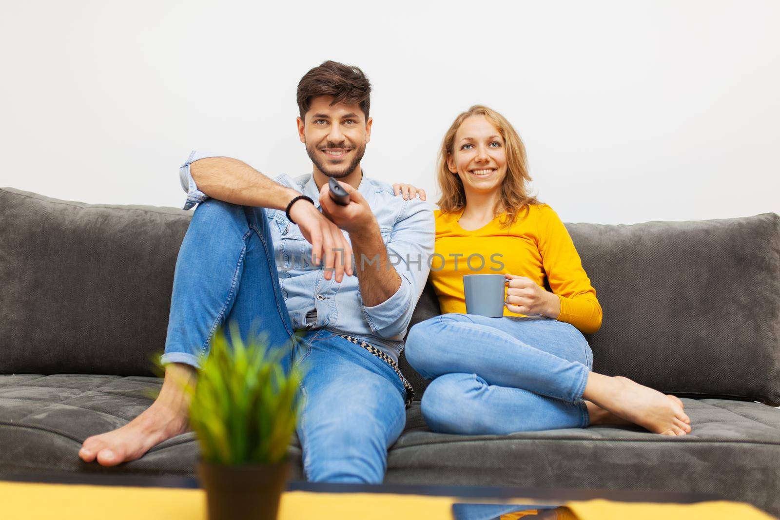 couple watching tv in living room by kokimk